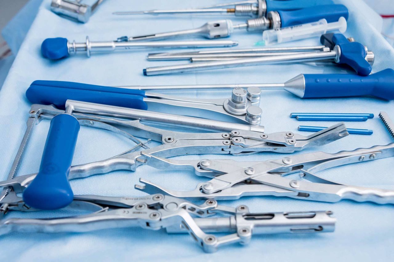 Metal medical tools with blue handles laid on pale blue cloth showcasing how SteriLogix's reprocessing reusable medical devices meets regulatory compliance.